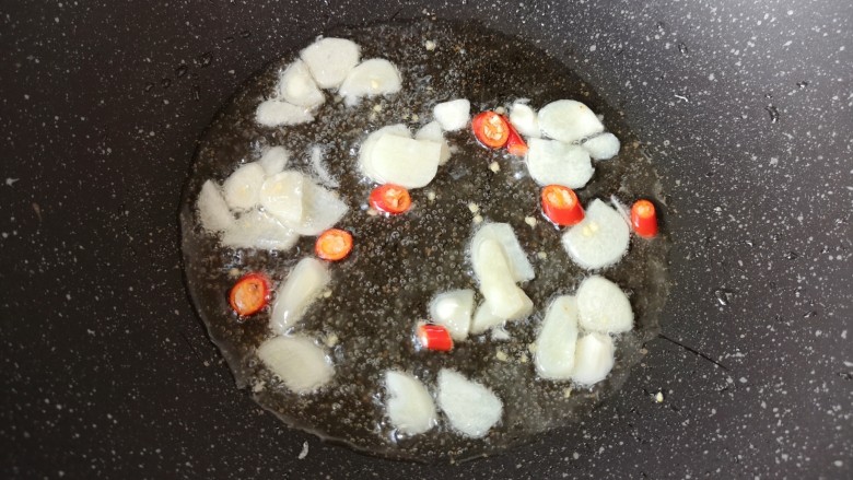 西葫芦炒腊肠,锅里继续倒油烧热，下入蒜片和小米椒炒香。