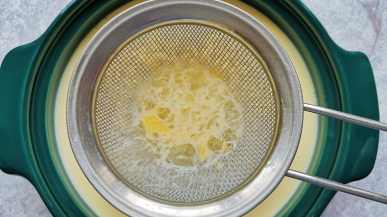 牛奶鸡蛋布丁,用网筛将牛奶蛋液过滤在蒸碗里。 