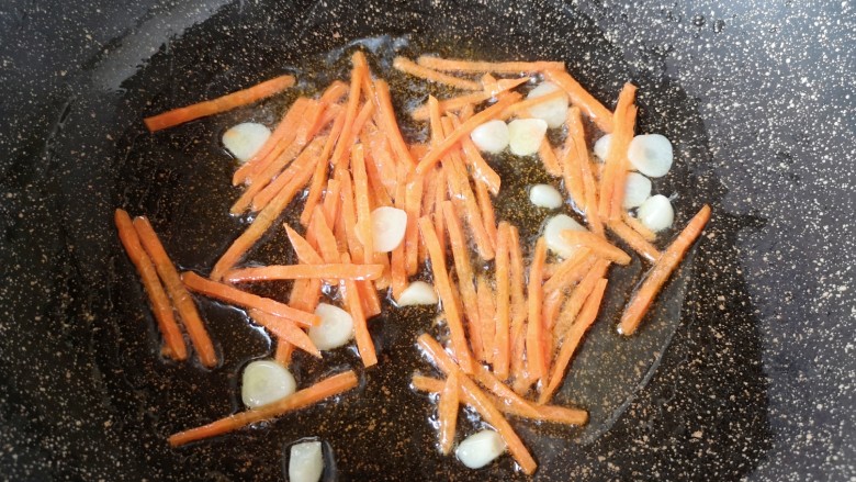 金针菇炒鸡蛋,锅里继续倒油烧热，下入蒜片炒香，下入胡萝卜丝翻炒均匀。