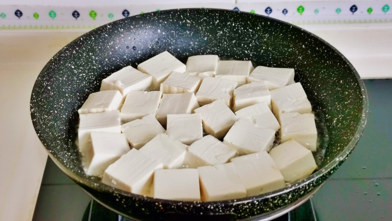 金针菇豆腐煲,起油锅加入切好的豆腐块中火煎。