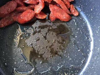 西葫芦炒腊肠,把腊肠推到锅的一侧，余油滤出来。