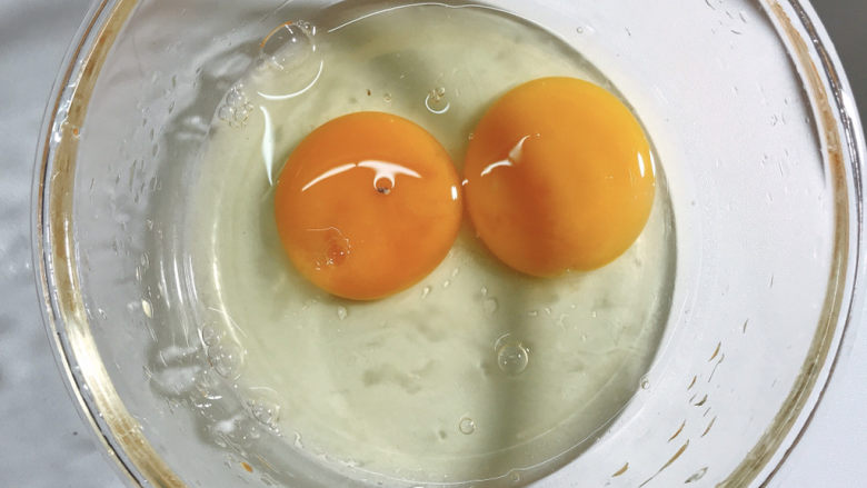 蚕豆炒鸡蛋,把两个鸡蛋磕入碗中