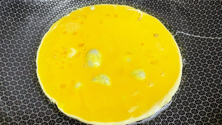 金针菇炒鸡蛋,锅中倒入适量的食用油烧热，倒入蛋液，煎至定型后铲碎