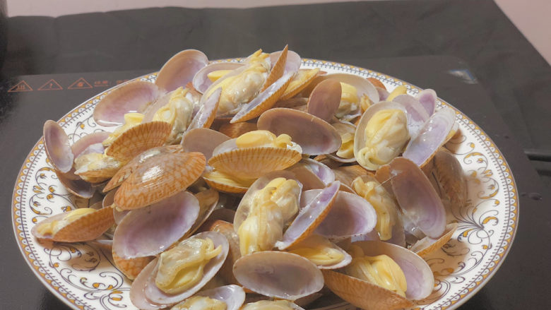 葱油花蛤,将煮开的花蛤盛到盘子里 