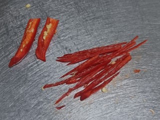 葱油花蛤,小米辣对半切开，拿刀刮去辣椒籽，切成细丝。我怕辣，只切了一个。如果不怕辣，可以直接切成圈，和葱末形状更搭配。