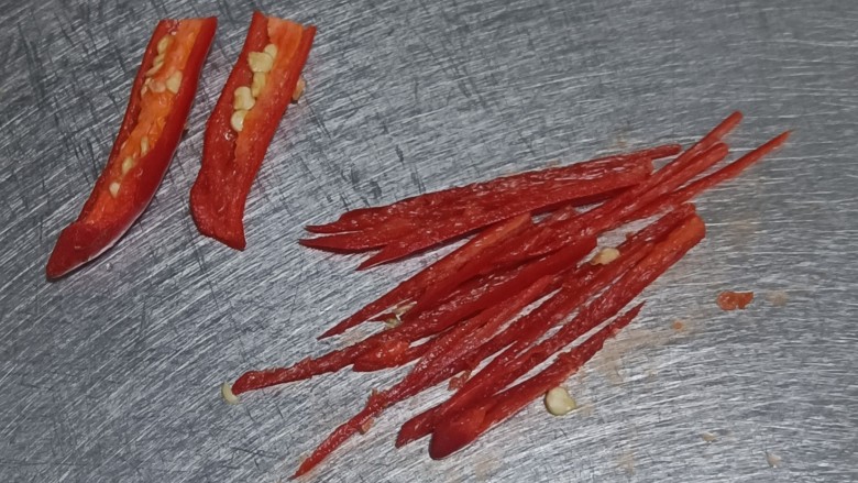 葱油花蛤,小米辣对半切开，拿刀刮去辣椒籽，切成细丝。我怕辣，只切了一个。如果不怕辣，可以直接切成圈，和葱末形状更搭配。