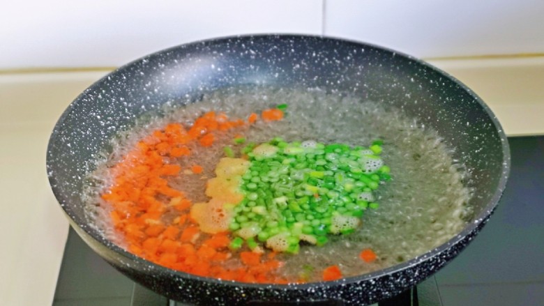 鸡蛋火腿炒饭,胡萝卜丁与蒜薹丁焯水: 锅中水烧开后，再下两丁大火煮1分钟捞出。