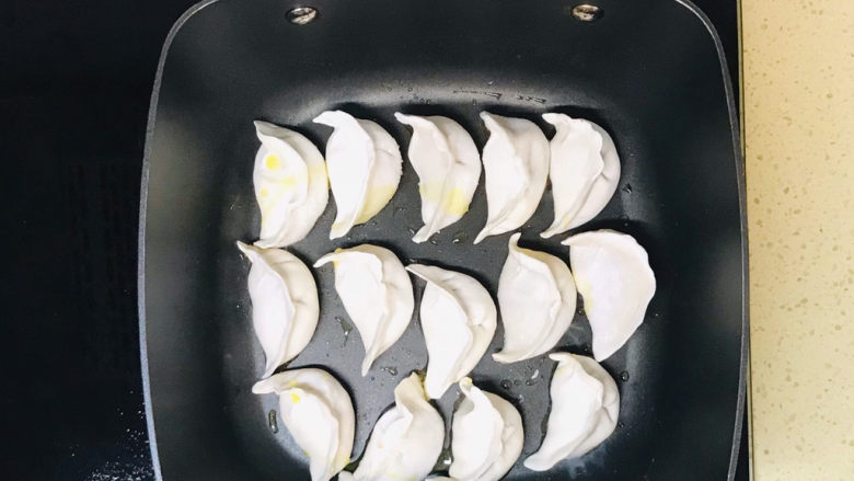 韭菜肉锅贴,不粘锅倒入适量的油，将锅贴整齐地摆放在锅里