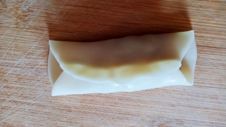 韭菜馅肉锅贴,将饺子皮对折捏住将馅儿料包在里面，两侧不要收口。