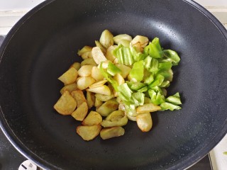 家常地三鲜,加入煎好的土豆块，加入青椒块翻炒至青椒变色，盛出备用