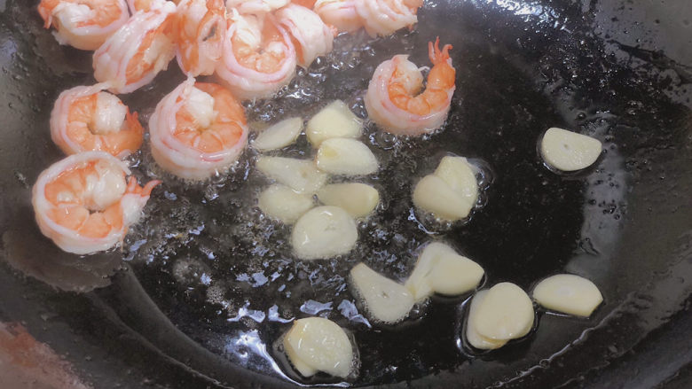芦笋虾球,将煎好的虾球拨到一边放入蒜片爆出香味
