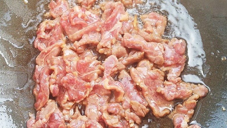豆角牛柳,锅中烧油，加入牛肉快速翻炒变色后盛出备用。