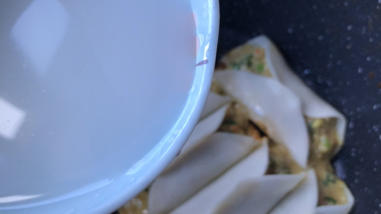 韭菜馅肉锅贴,接着沿锅边倒入淀粉水，水量差不多是饺子的一半高。