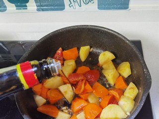 西红柿土豆炖牛肉,倒入土豆、胡萝卜翻炒，倒入生抽。