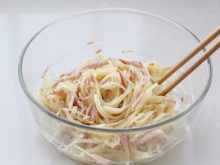 家常土豆饼,用筷子将食材与调味料混合搅拌均匀，土豆丝和火腿上面都要裹上蛋清。