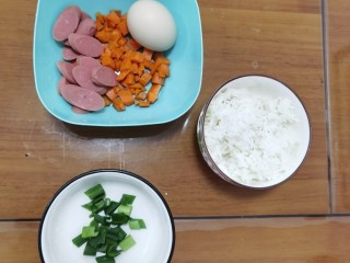 鸡蛋火腿炒饭,准备熟米饭一碗，胡萝卜🥕洗净去皮切块，火腿肠切块，还有葱花和鸡蛋。