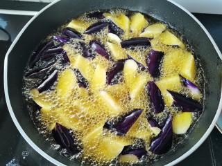 家常地三鲜,锅里倒入多点油，放入茄子，土豆炸软捞出沥油
