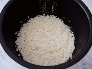 什锦香肠焖饭,把淘洗干净的大米放入电饭煲内胆中
