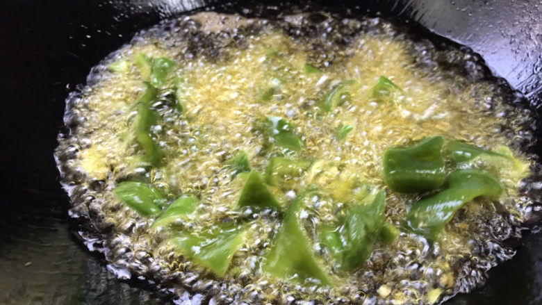 家常地三鲜,青椒下锅炸至表面变色，捞出放在土豆上