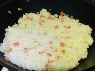 鸡蛋火腿炒饭,锅加食用油，加入米饭，加入火腿粒，翻炒一会
