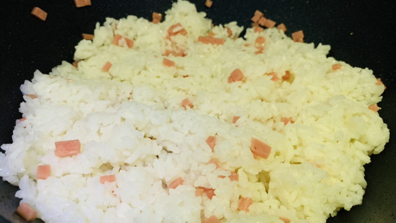 鸡蛋火腿炒饭,锅加食用油，加入米饭，加入火腿粒，翻炒一会
