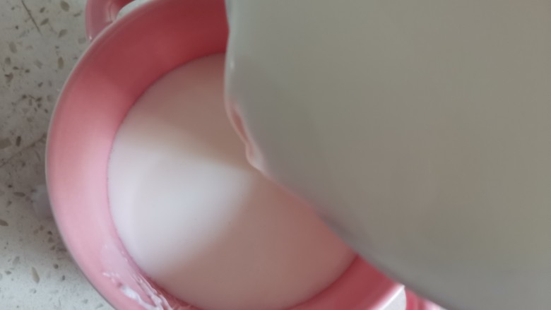 芒果双皮奶,摁着原来的小孔从边缘把牛奶倒到碗中，此时那层奶皮应该浮上来