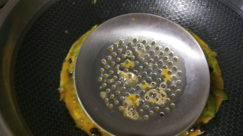 苦瓜摊鸡蛋,用漏勺把鸡蛋液均匀漏在苦瓜上。