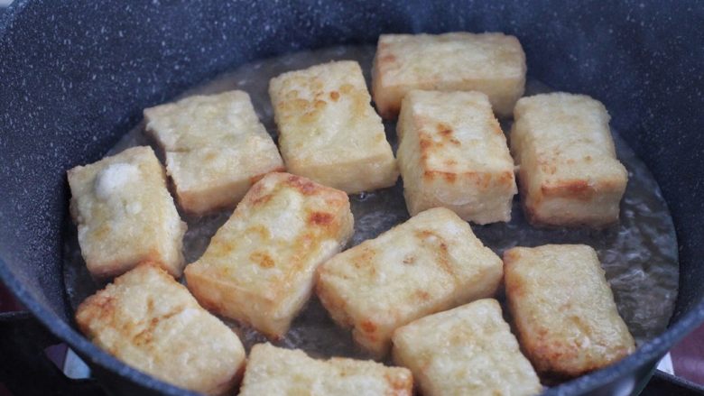 韭菜豆腐,锅中倒入食用油，将裹了淀粉的豆腐块放进去，小火煎至表面呈焦黄状盛出。