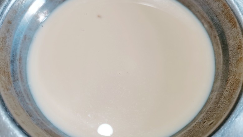 芒果双皮奶,过一遍筛子之后再用筷子挑起奶皮，再把牛奶轻轻地倒回原来的碗里