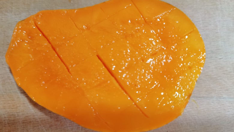 芒果双皮奶,准备新鲜的芒果用刀从中间切开，再交叉划几刀