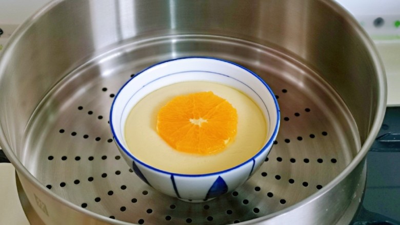水嫩蒸蛋,待蛋羹表面凝固后加入一勺橙子，盖上盖子再蒸5分钟。