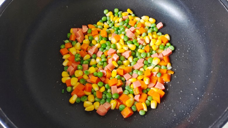 彩蔬火腿丁,倒入胡萝卜丁、玉米粒、豌豆粒翻炒片刻