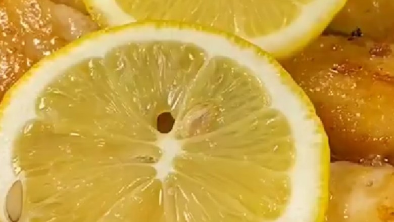 柠香鸡翅,挤出水分的柠檬在放在鸡翅上面中小火煎制。