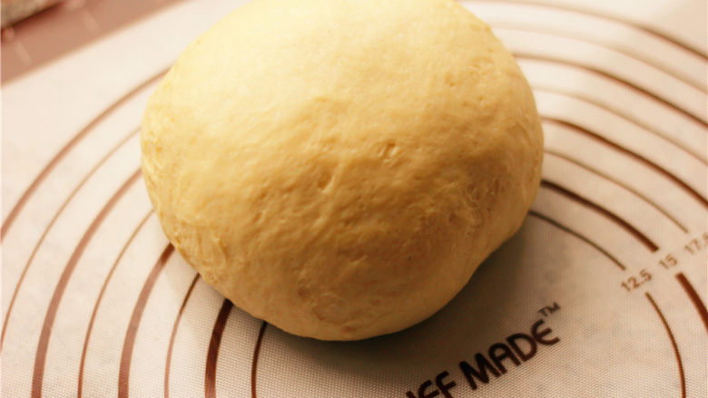 奶香小面包,发酵至原面团两倍大小的时候，用手指蘸一下水，在中间扎一下，小孔不回缩证明面团发酵好了。取出面团，放在揉面垫上排气。