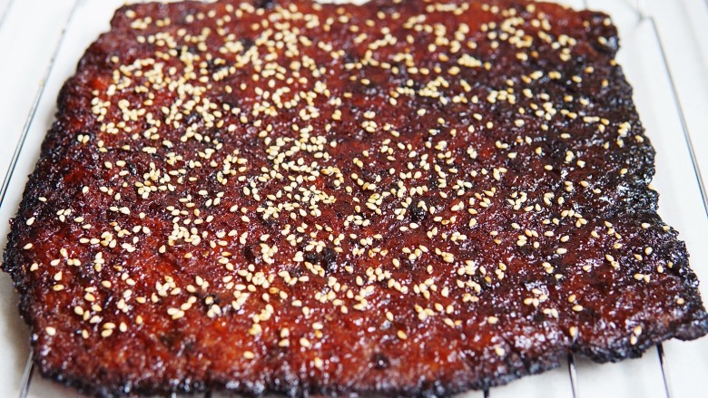 蔓越莓香浓猪肉脯,7、时间到，取出烤盘翻面，刷一层蜂蜜，撒一层白芝麻再烤十分钟，现在触摸能感觉得到肉脯紧实没有水分。