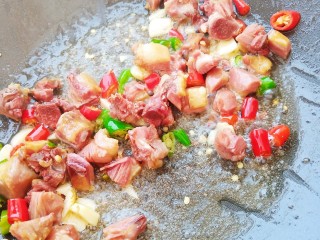 腊鸭腿炒白菜杆,加入蒜粒和准备好的辣椒炒出香气。