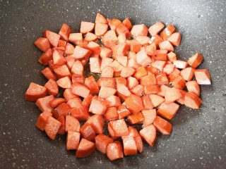 彩蔬火腿丁,炒锅内倒适量的食用油烧热，下入火腿肠翻炒至表面焦黄。