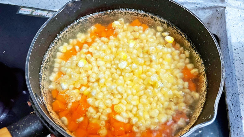 彩蔬火腿丁,锅中烧开水，放入胡萝卜和玉米焯熟