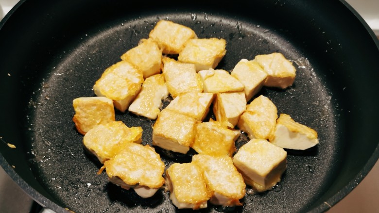 椒盐豆腐,煎锅加入食用油，放入包裹了鸡蛋液的豆腐，煎制。