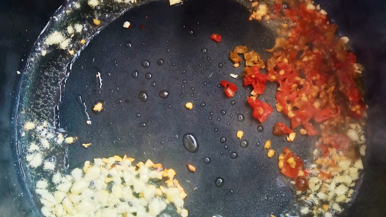 茄泥肉丸,锅中烧油，加入蒜末和泡椒末炒出香气。