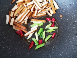西芹炒香干,将炒好的香干用铲子拨在锅的一边，下入葱段和干红辣椒炝一下。 