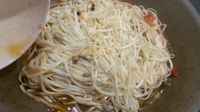 豆角、土豆、番茄焖面,几分钟后，原来的菜汤几乎炒干了，这时候沿着锅边放入前面盛出来的汤。