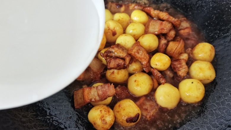 五花肉焖小土豆,倒入清水没过食材，大火烧开转中小火焖10分钟