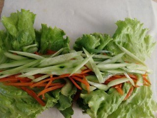 素卷三丝,把黄瓜条，胡萝卜条，青椒条铺在生菜上。