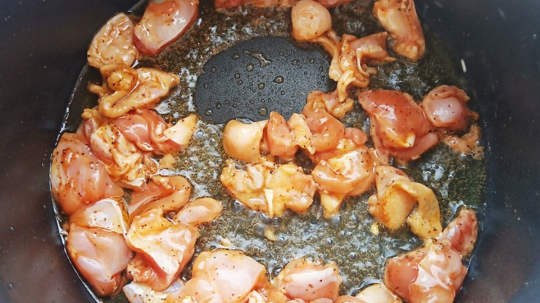 杏鲍菇炒鸡丁,锅中倒入比平时炒菜略多的油，加入腌制好的鸡肉丁翻炒均匀。