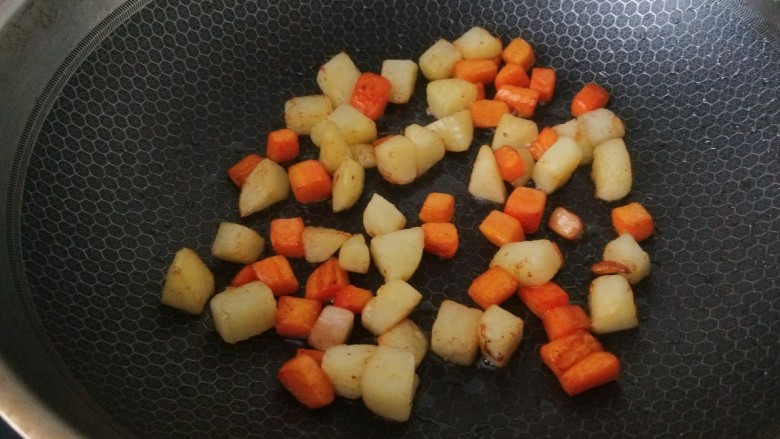 杏鲍菇炒鸡丁，,锅中倒入适量油烧热倒入胡萝卜土豆丁煸炒上色。