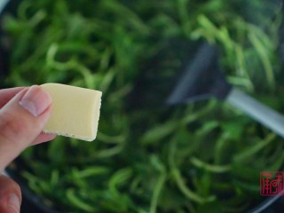 清香解暑的蒜香马兰头,8、待马兰头炒软后放入一小块奶油。