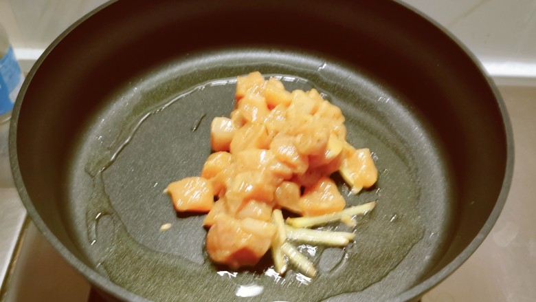 杏鲍菇炒鸡丁,起油锅放入食用油，油热后放入姜丝炒出香味，放入腌制好的鸡丁翻炒。