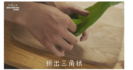 粽子一定要吃咸的|咸蛋黄肉粽最经典,粽叶剪掉根部，将粽叶弯折上去，再弯折到右边，折出三角状。