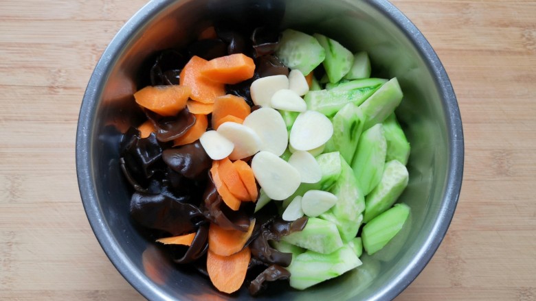黄瓜拌木耳,将处理好的黄瓜、胡萝卜和木耳一起放入盆里，放上蒜片。